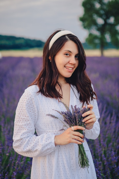 Mulher linda em um vestido branco no campo de lavanda, hora do pôr do sol