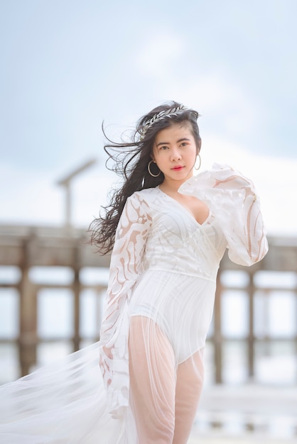 Mulher linda em um vestido branco passeando feliz na praia