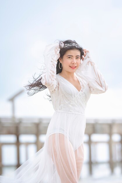 Mulher linda em um vestido branco passeando feliz na praia