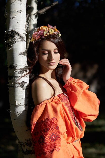 Mulher linda em um vestido laranja com uma coroa de flores