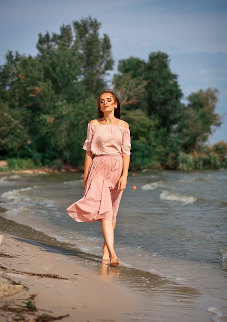 Mulher linda em um vestido longo na praia