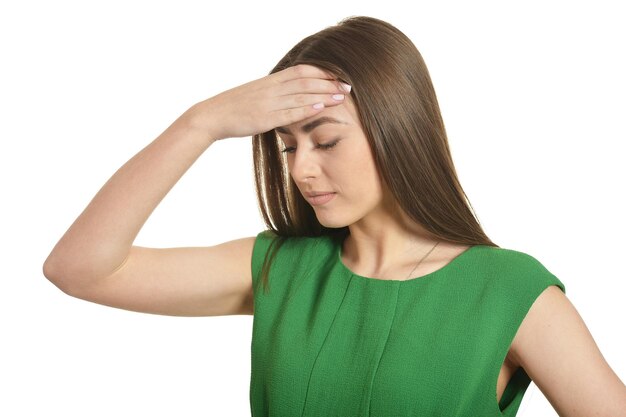 Mulher linda em um vestido verde com dor de cabeça em fundo branco