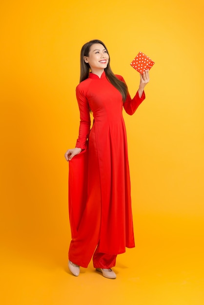 Mulher linda em um vestido vermelho ao dai segurando uma caixa de presente