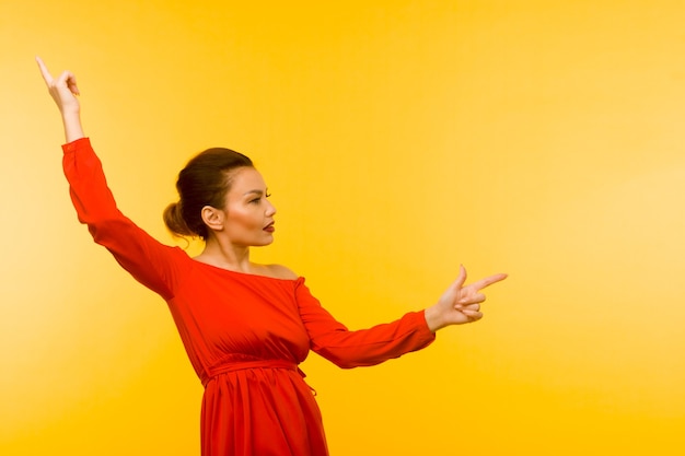 Mulher linda em um vestido vermelho apontando o dedo sobre fundo amarelo