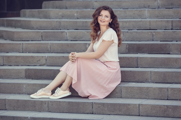 Mulher linda jovem modelo com cabelo perfeito posando na cidade. Retrato de moda estilo de vida ensolarado