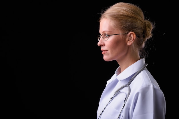 Mulher linda médica com cabelo loiro contra parede preta