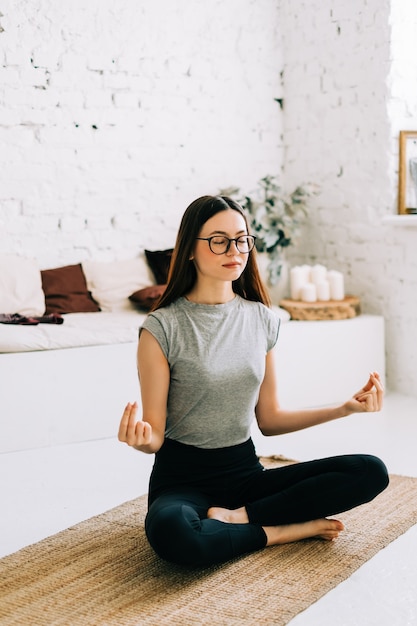 Mulher linda morena fitness meditando fazendo ioga dentro de casa em casa