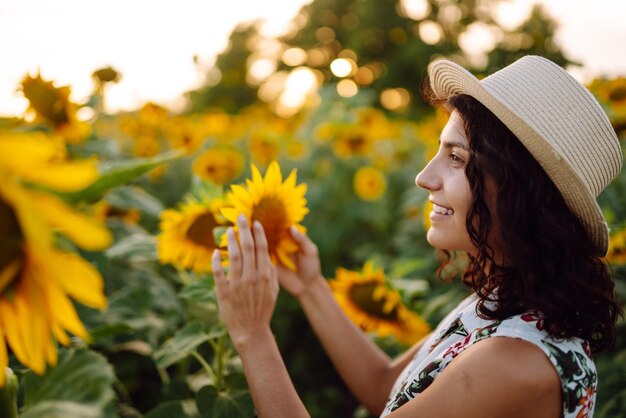 Mulher linda posando em um campo de girassóis em um vestido e chapéu conceito de estilo de vida de moda