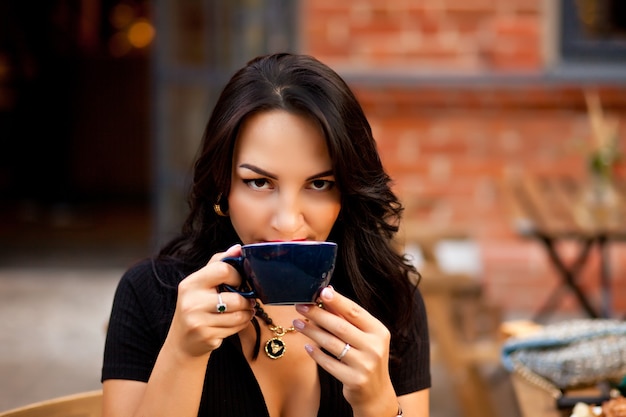 Mulher linda tomando café em um café e comendo croissant