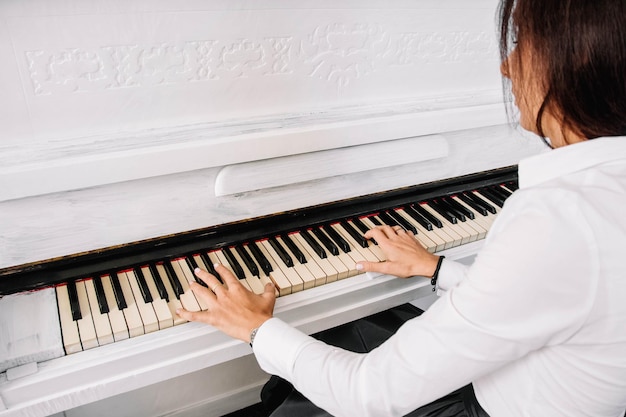 Mulher linda vestida de vestido branco tocando piano branco