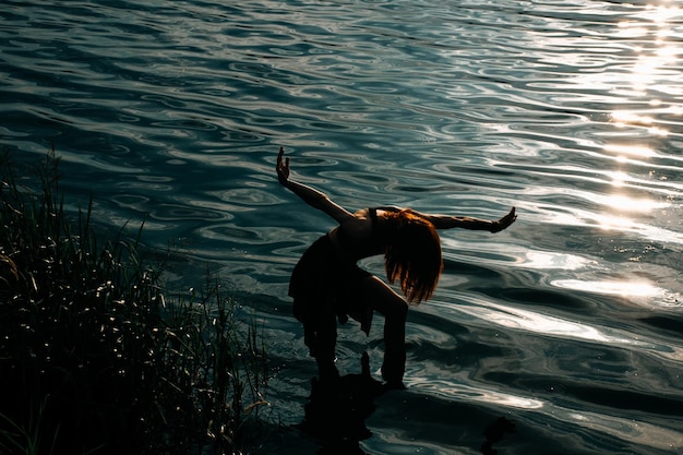 Mulher livre forte dançando uma dança livre xamânica ritual entre as ondas ao pôr do sol.