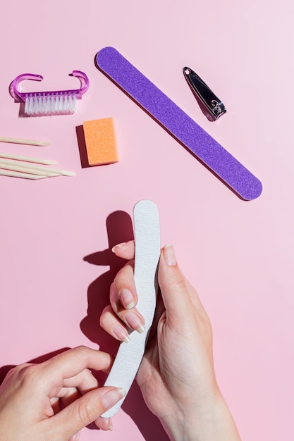 Mulher lixando as unhas Mãos femininas e ferramentas de manicure Cuidado profissional das unhas Autocuidado Faça manicure sozinha alinhando as unhas com uma lixa de unhas Manicure em casa