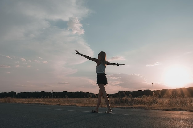 Mulher loira andando na estrada ao pôr do sol em shorts