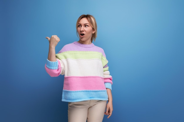 Mulher loira bonita com aparência casual surpresa mostrando parede com espaço de cópia em fundo azul