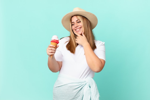 Mulher loira bonita e curvilínea sorrindo com uma expressão feliz e confiante com a mão no queixo