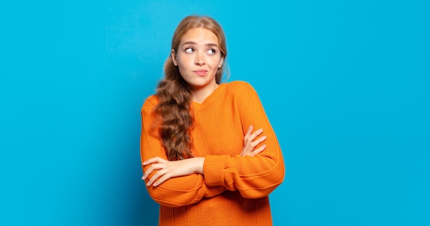 Mulher loira bonita encolhendo os ombros, sentindo-se confusa e incerta, duvidando com os braços cruzados e olhar perplexo