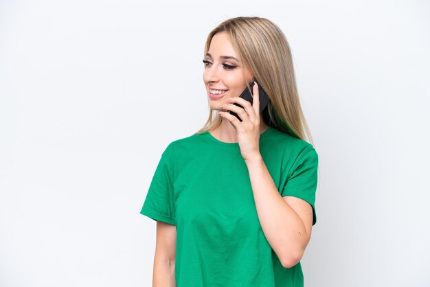 Foto mulher loira bonita isolada em fundo branco, mantendo uma conversa com o celular com alguém