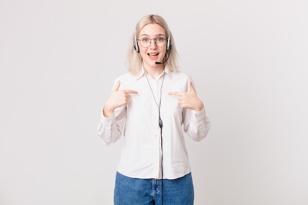 Mulher loira bonita se sentindo feliz e apontando para si mesma com um conceito de telemarketing animado