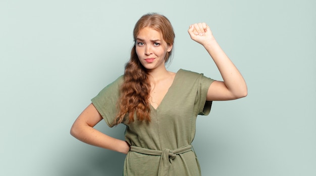 Foto mulher loira bonita se sentindo séria, forte e rebelde, levantando o punho, protestando ou lutando pela revolução