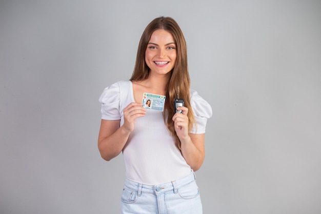 Mulher loira brasileira segurando a carteira de habilitação e a chave do carro Tradução em inglês carteira nacional de habilitação