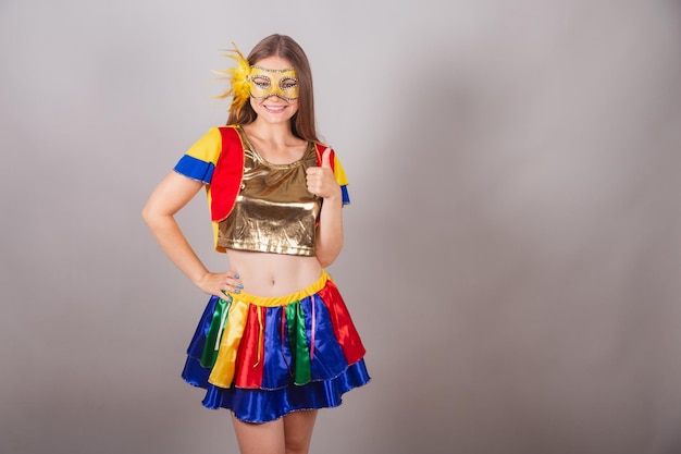 Mulher loira brasileira vestida com roupa de frevo máscara de carnaval como sinal positivo