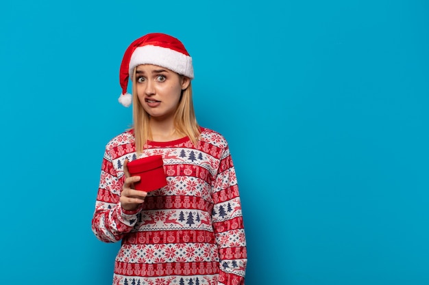 Mulher loira com chapéu de papai noel se sentindo perplexa e confusa, com uma expressão estúpida e atordoada olhando para algo inesperado