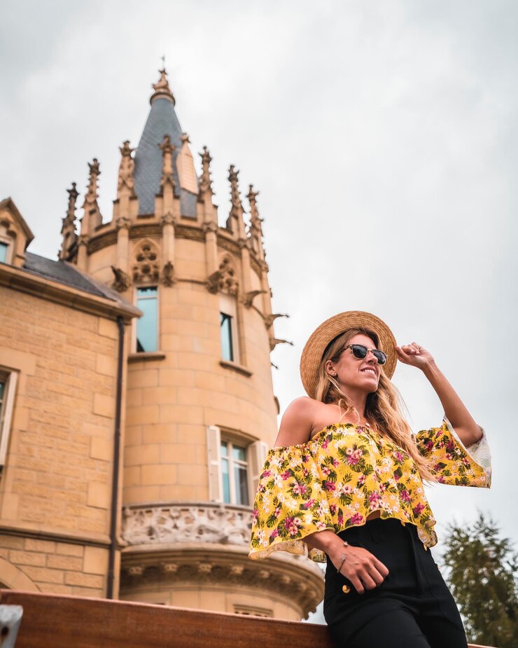 Foto mulher loira com uma roupa vintage amarela com um chapéu em um castelo