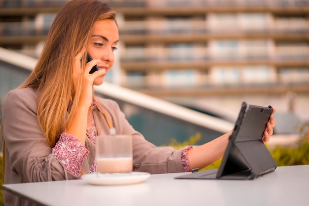 Mulher loira comercial tomando um café descafeinado no café da manhã em uma chamada de trabalho