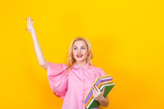 Mulher loira de blusa rosa com pilha de livros