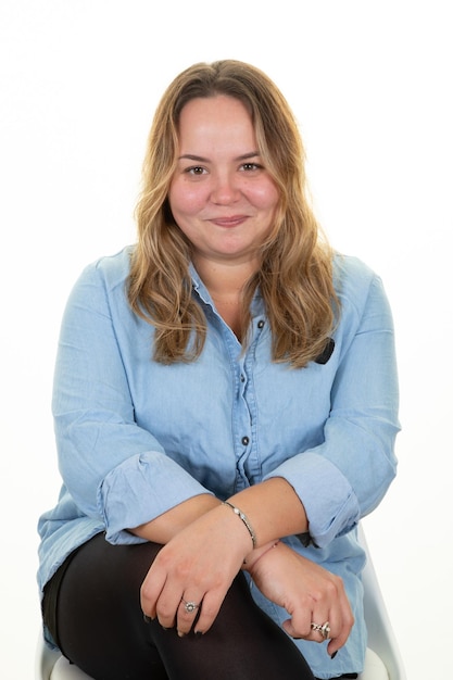 Mulher loira de tamanho grande com cabelo comprido, loira, sentada, camisa azul sobre fundo branco