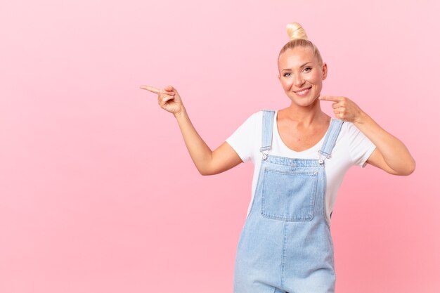 Mulher loira e bonita sorrindo com confiança apontando para o próprio sorriso largo