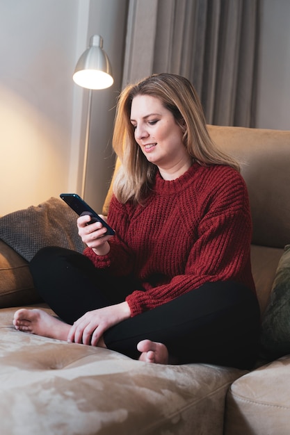 Mulher loira em casa com smartphone