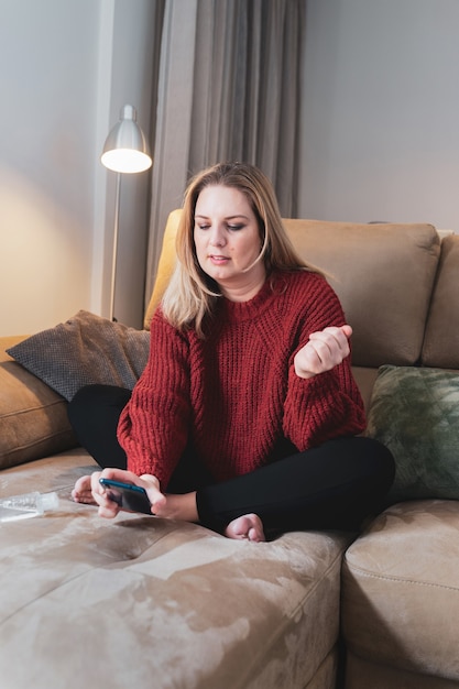 Mulher loira em casa com smartphone