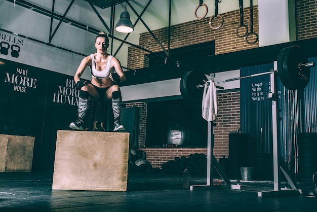 Foto mulher loira em forma pulando treinamento de caixa malhando na academia