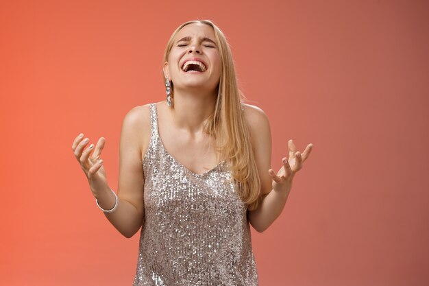 Mulher loira encantadora feliz aliviada graças a Deus gritando sim celebrando regozijando-se vitória em pé fundo vermelho feche os olhos rindo felicidade cerrar os punhos vitória triunfo gesto, sonho tornado realidade.