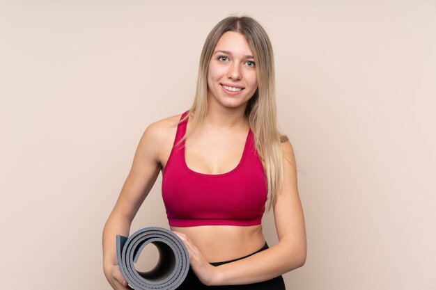 Mulher loira esporte jovem com uma esteira e sorrindo