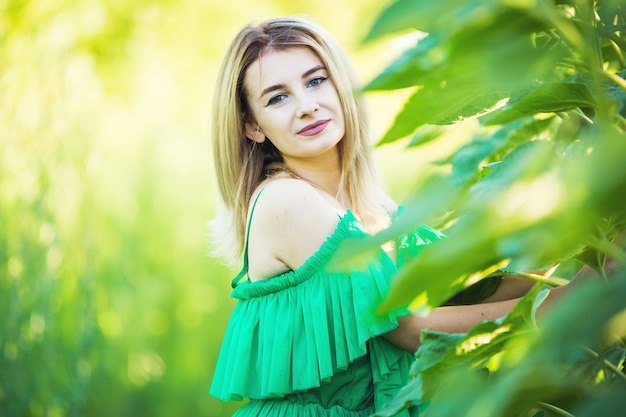 Mulher loira europeia com um vestido verde na natureza com girassóis