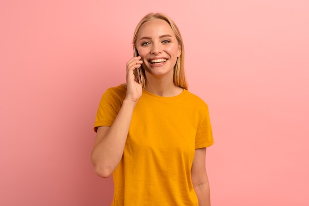 Mulher loira fala ao telefone com amigos. expressão alegre.