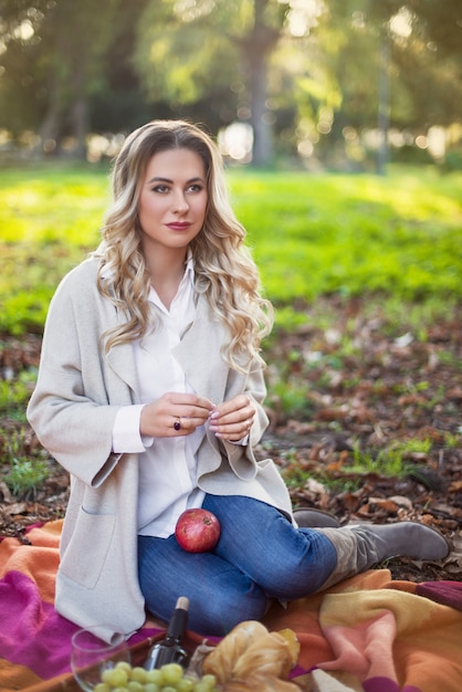 Mulher loira fazendo um piquenique no parque