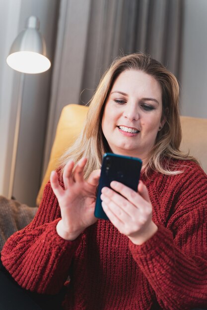 Foto mulher loira feliz em casa usando smartphone