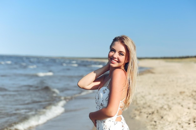 Mulher loira feliz em êxtase de felicidade livre na praia do oceano em pé e posando.