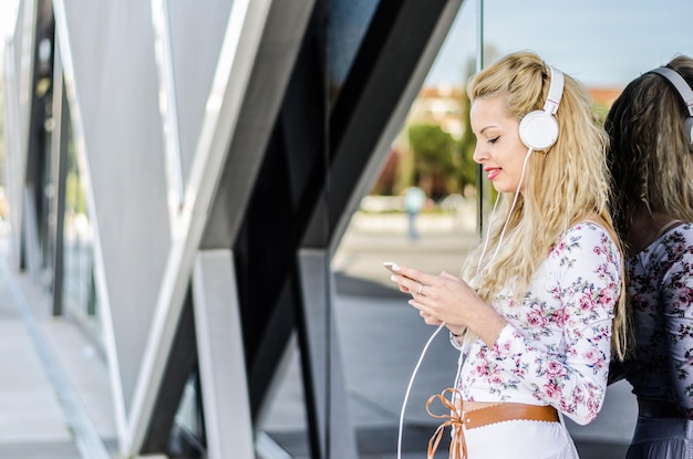 Mulher loira feliz isolada ouvindo música com fones de ouvido e