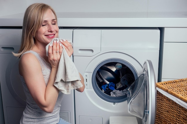 Mulher loira feliz lavando roupas se sentindo feliz com aroma de roupa macia e fresca aromaterapia amaciante de tecido