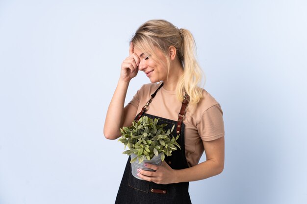 Mulher loira jardineiro segurando uma planta sobre rir isolado