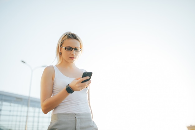 Mulher loira lendo uma mensagem no telefone