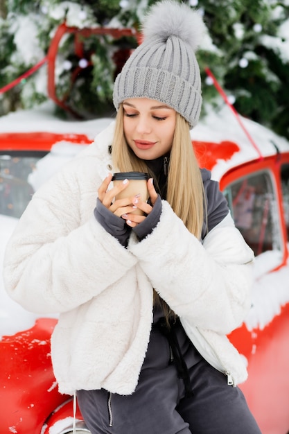 Mulher loira maravilhosa tomando café no parque de inverno