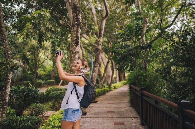 Mulher loira mochileiro viajante andando tirando fotos na floresta tropical, natureza de aventura de viagem na China, destino belo turista Ásia, viagem de férias de férias de verão, cópia espaço para banner