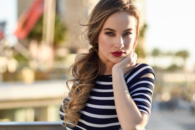 Mulher loira, modelo da moda, sentado no meio urbano.