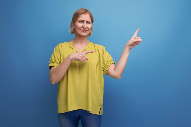 Mulher loira mostrando o dedo no espaço em branco da parede