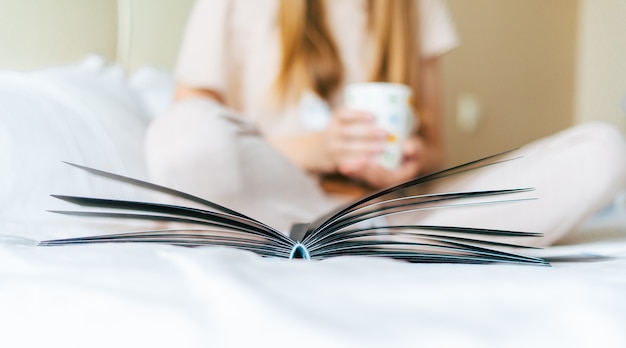 Mulher loira na cama com livro